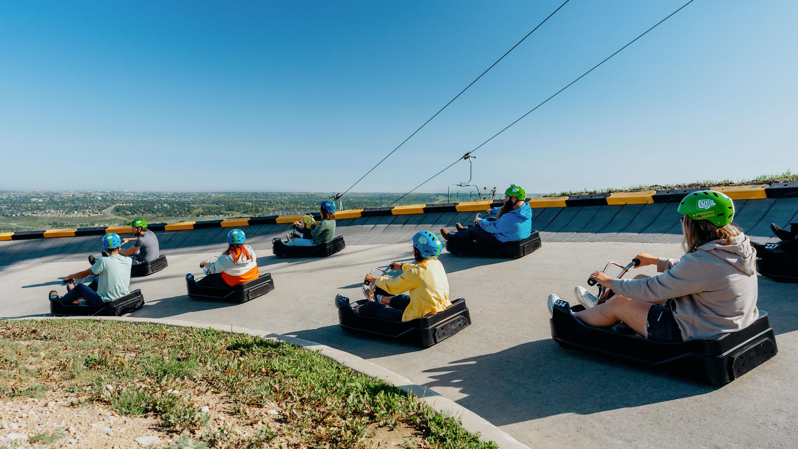 A large group of people cruise around a corner on the track at Downhill Karting Calgary.